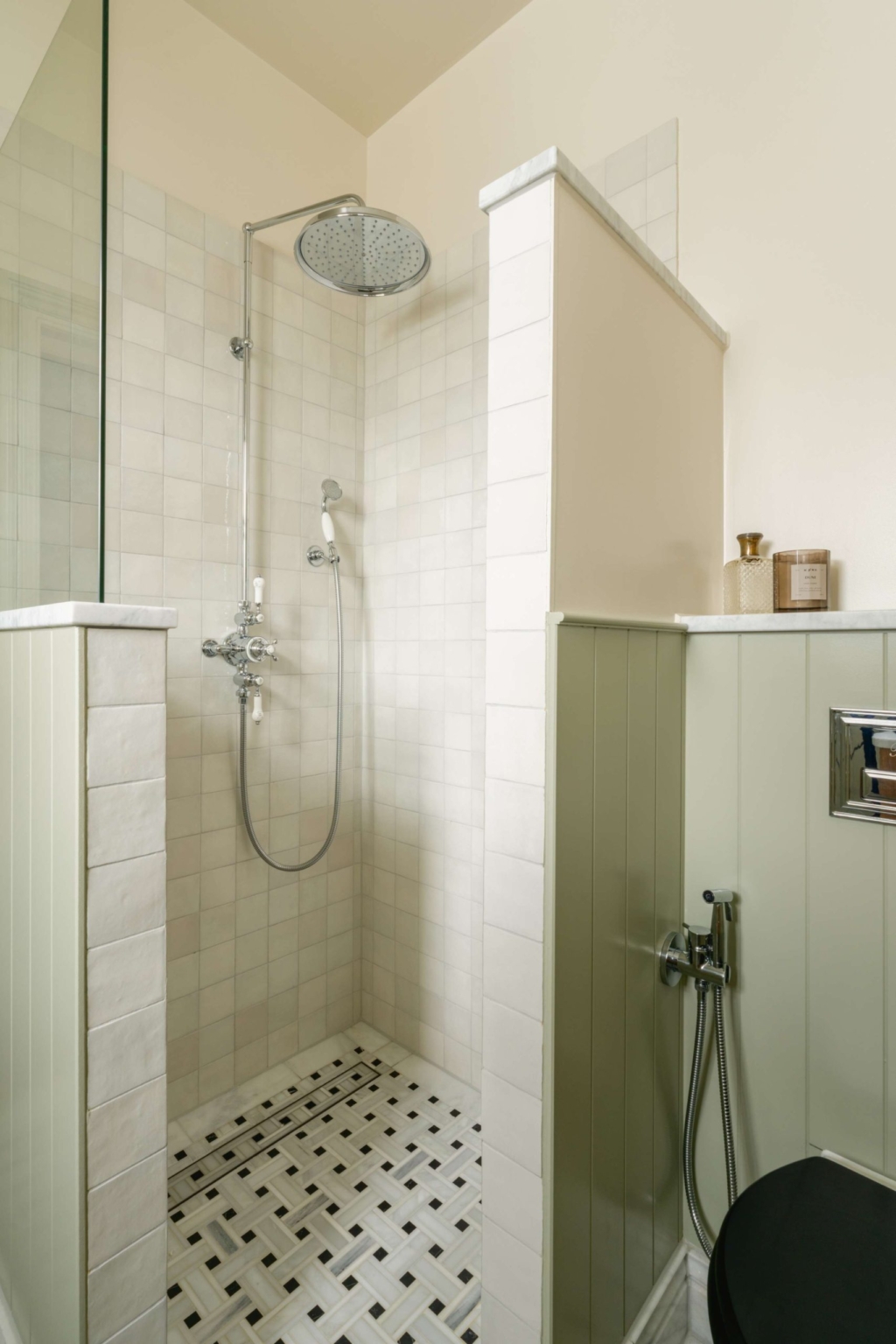 Walk-in shower with pale East Hampton marble tiles, traditional polished chrome shower fittings and basketweave mosaic flooring.