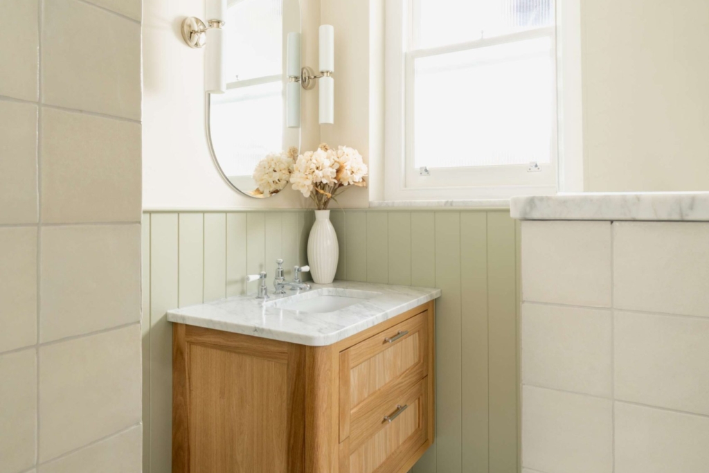 Oak vanity with marble basin, soft sage panelling and basketweave marble flooring in the Hampton family bathroom in Hove.