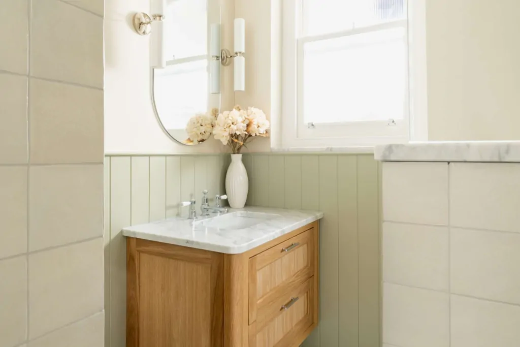 Oak vanity with marble basin, soft sage panelling and basketweave marble flooring in the Hampton family bathroom in Hove.